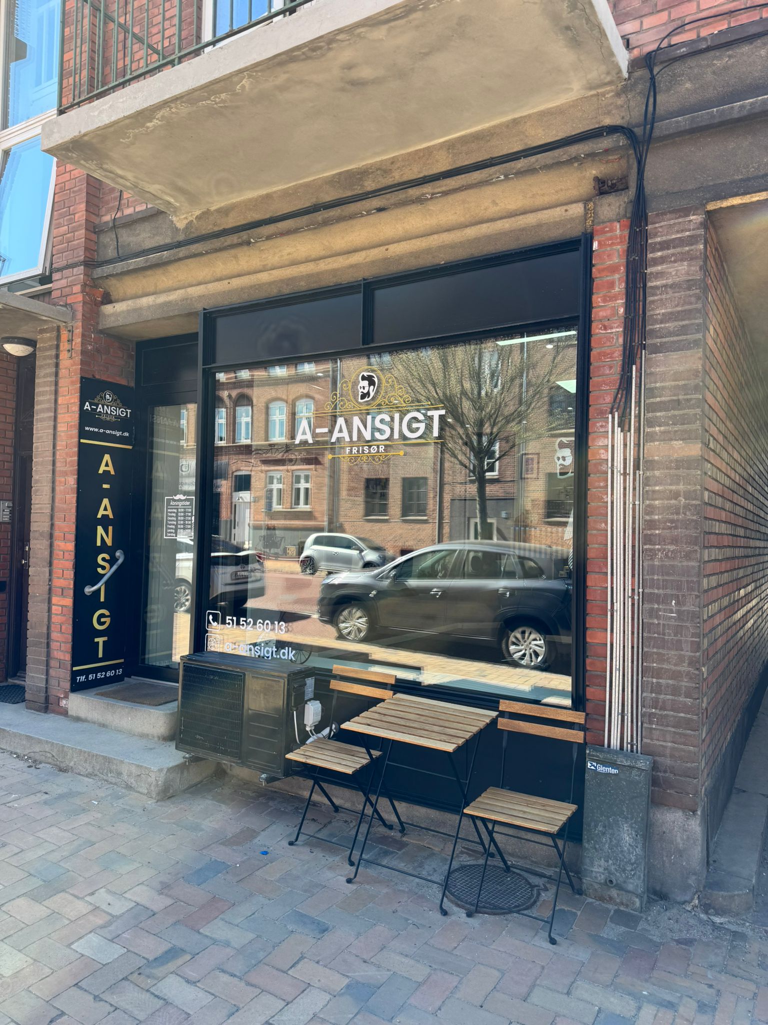 Facaden på Skibhusvej 136 med A-Ansigt-skilt og café-bord ved indgangen